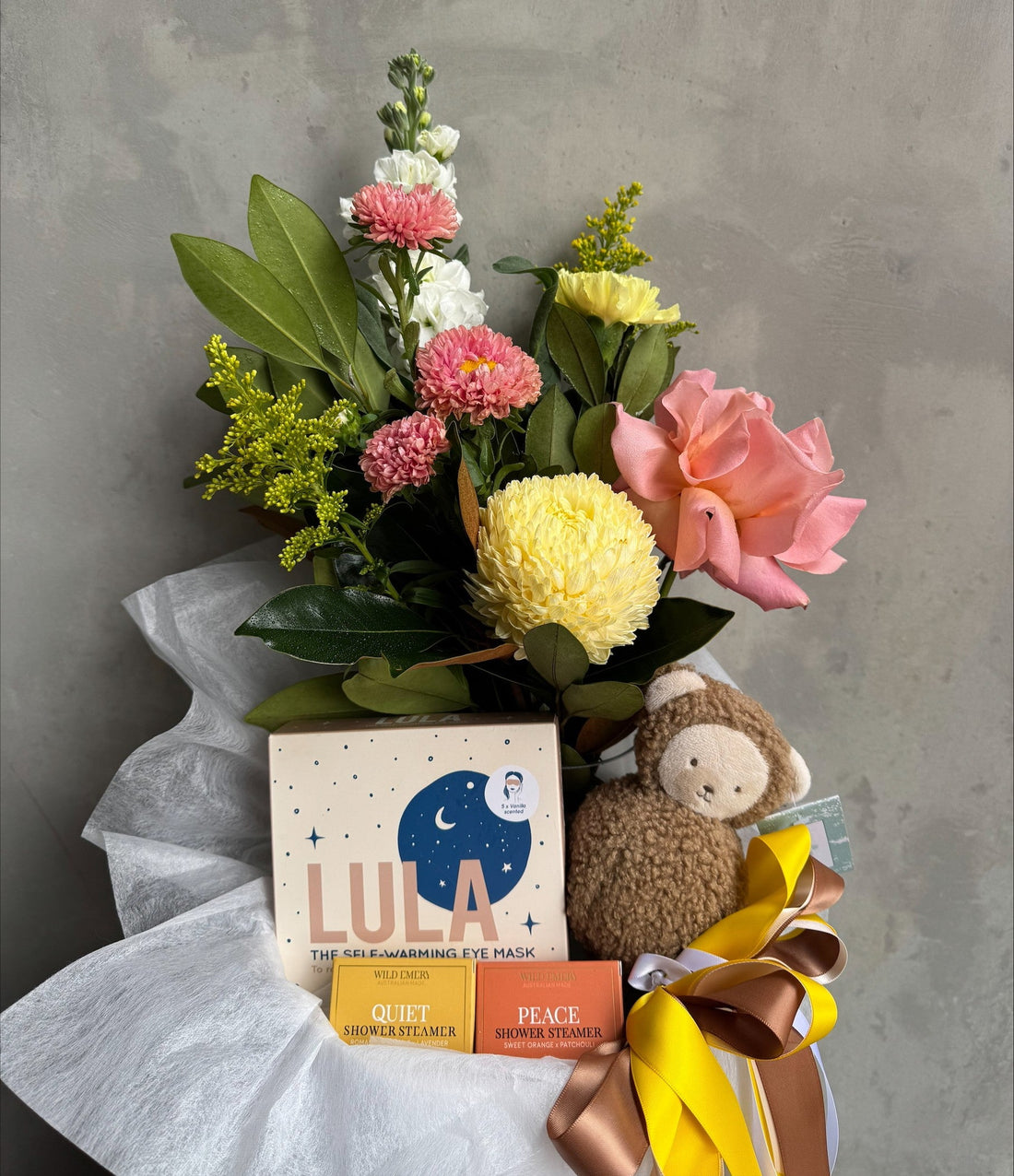 Bouquet of flowers with a Lula product and plush toy on a gray background